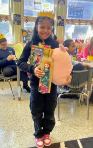 An elementary age student holds toys she received