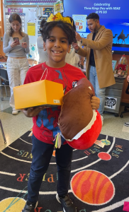 An elementary age student holds toys he received