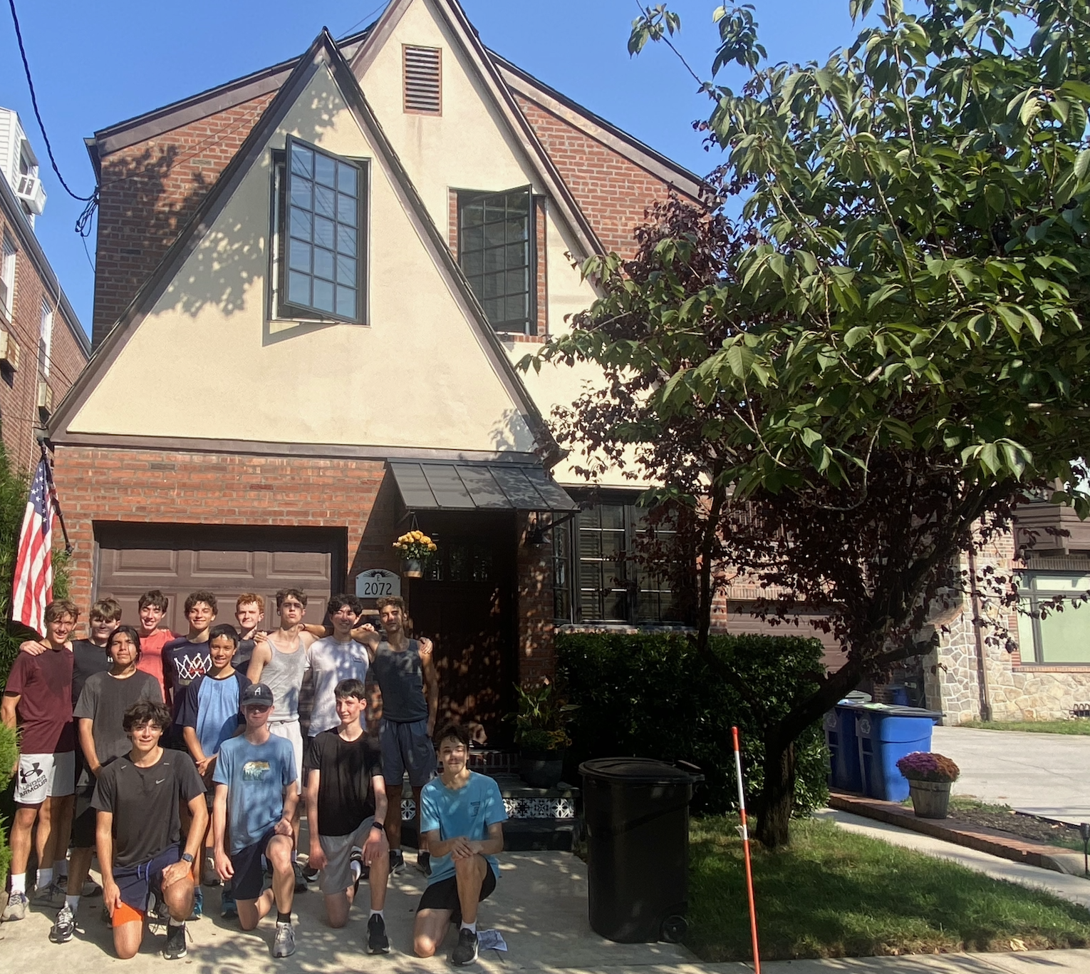 Members of the team stand in front of a house.