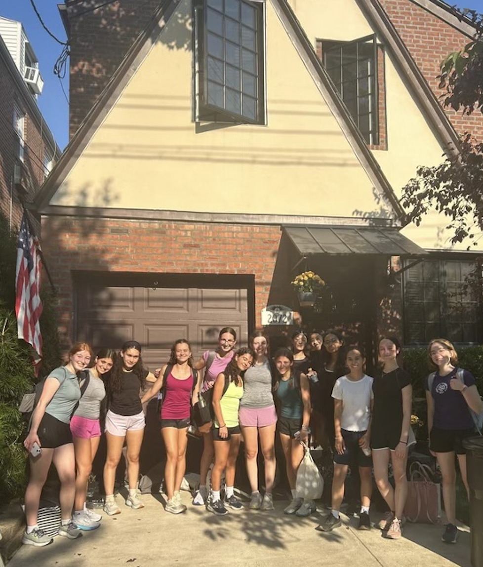 Members of the team stand in front of a house.