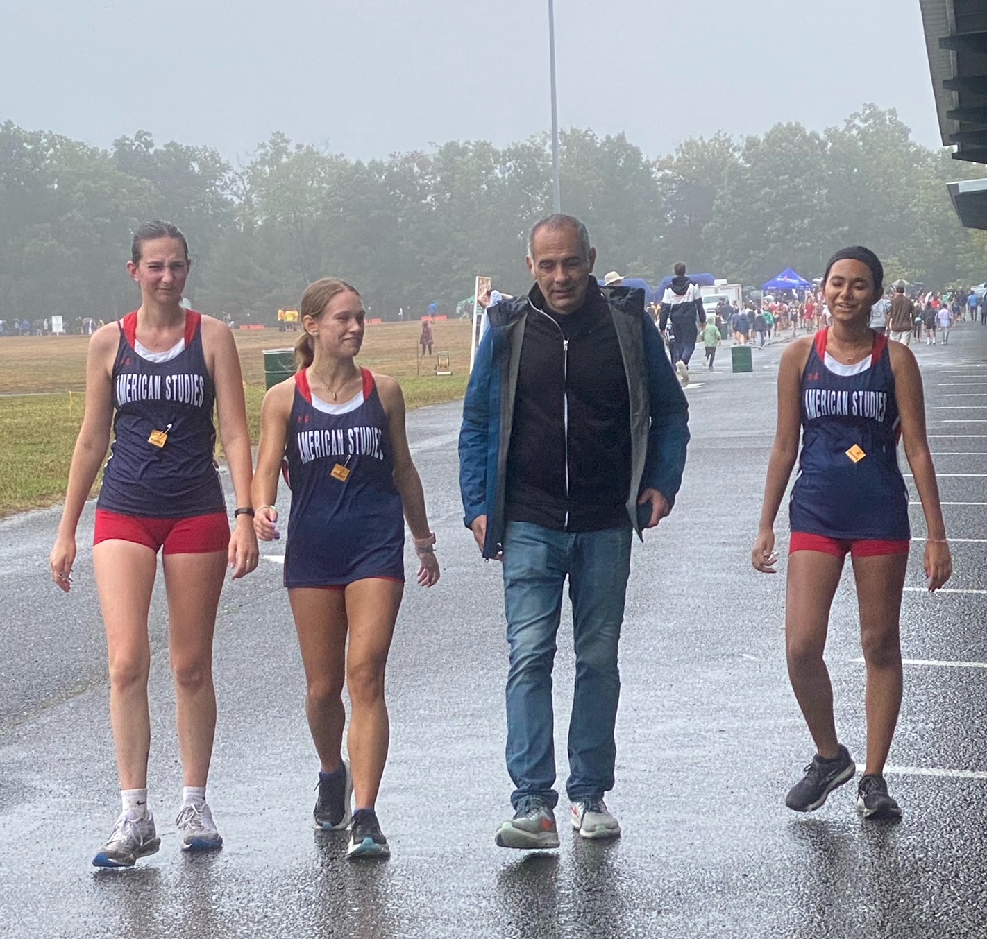 Three athletes and their coach walk toward the camera