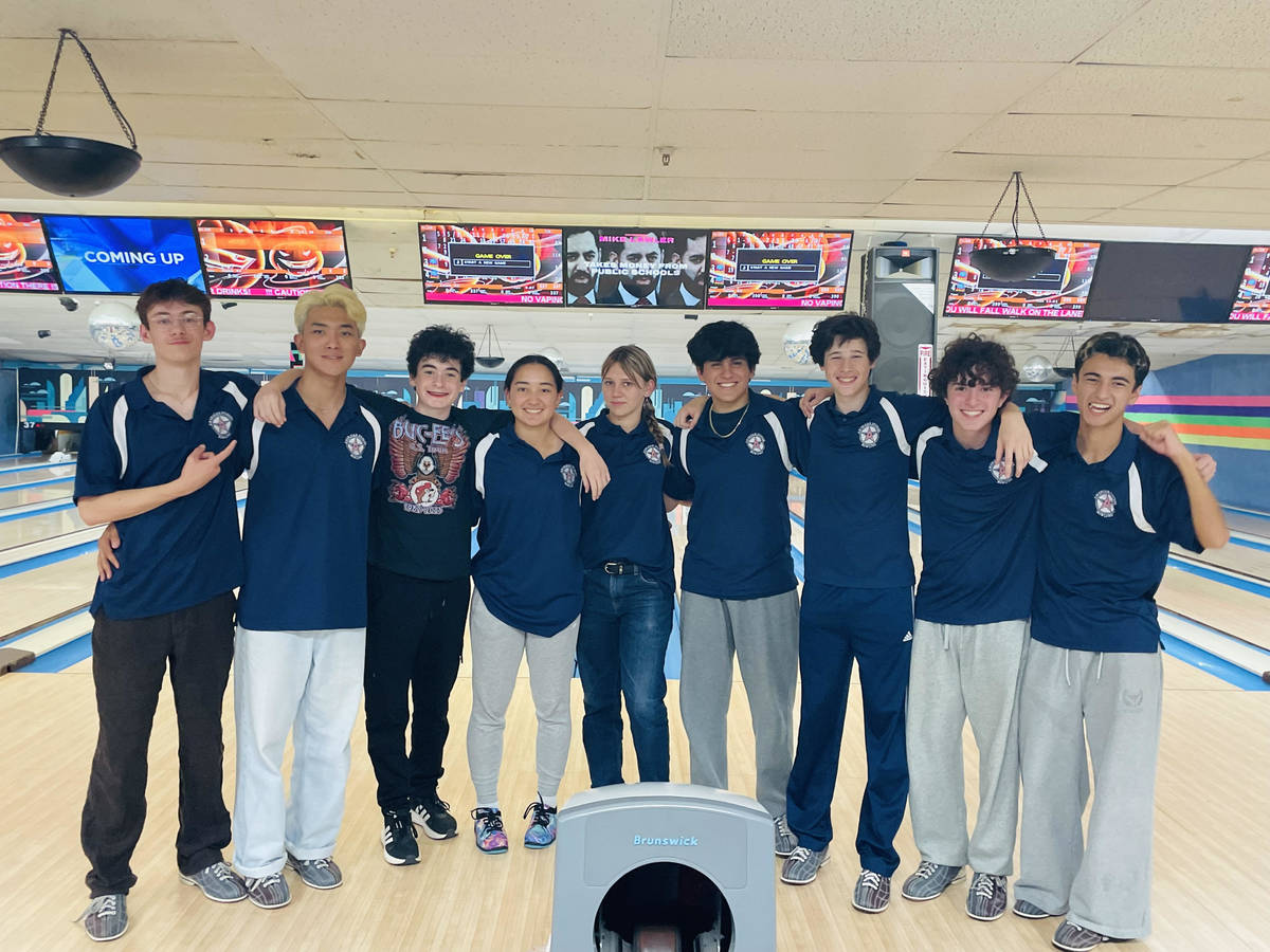 Members of the bowling team stand side by side with a bowling alley behind them.