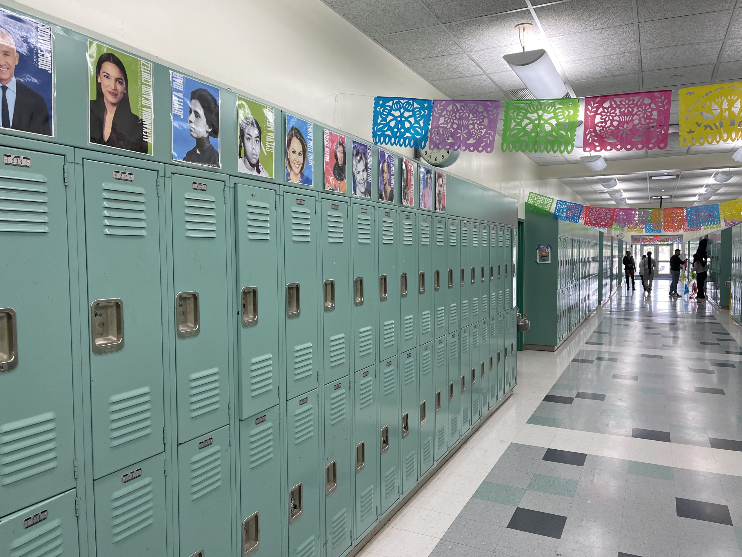 Lockers in a school hallway are decorated with signage of famous Latinx Pioneers.