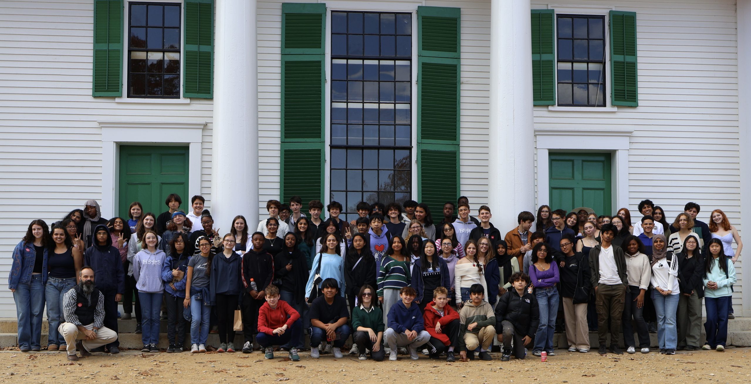 90 Students stand in three rows in front of the townhall meeting house.