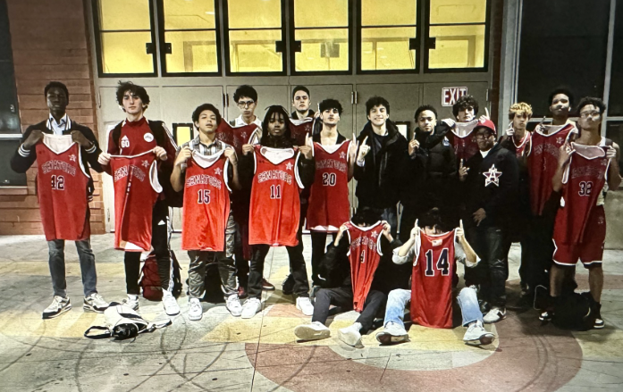 Team members stand shoulder to shoulder holding up their jerseys in front of them.