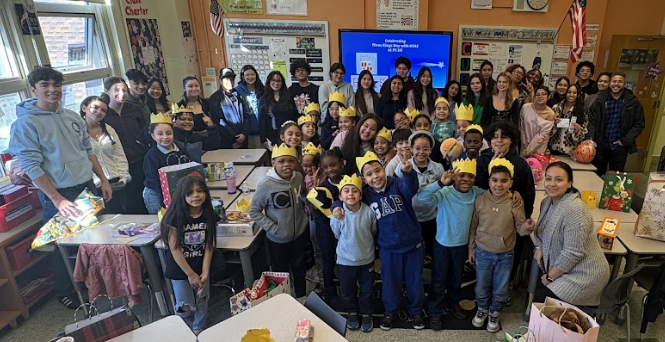 A class of elementary aged students cheer with older teen students standing behind them,