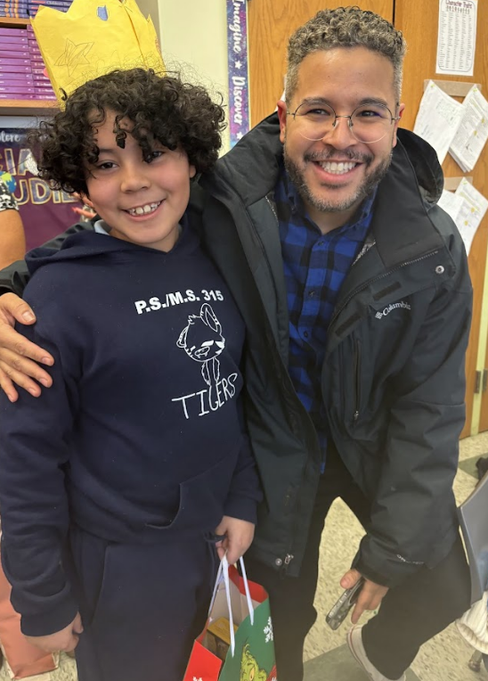 An elementary age student stands with an adult facing the camera.