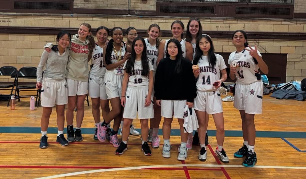 Members of the girl's basketball team stand side by side in two rows following a victory.