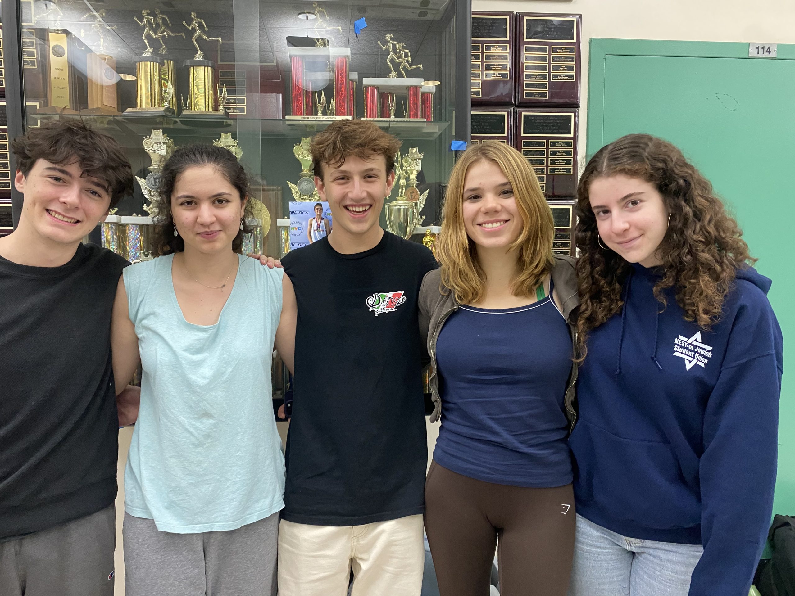 Leaders of the debate team stand with arms over one another's shoulders.