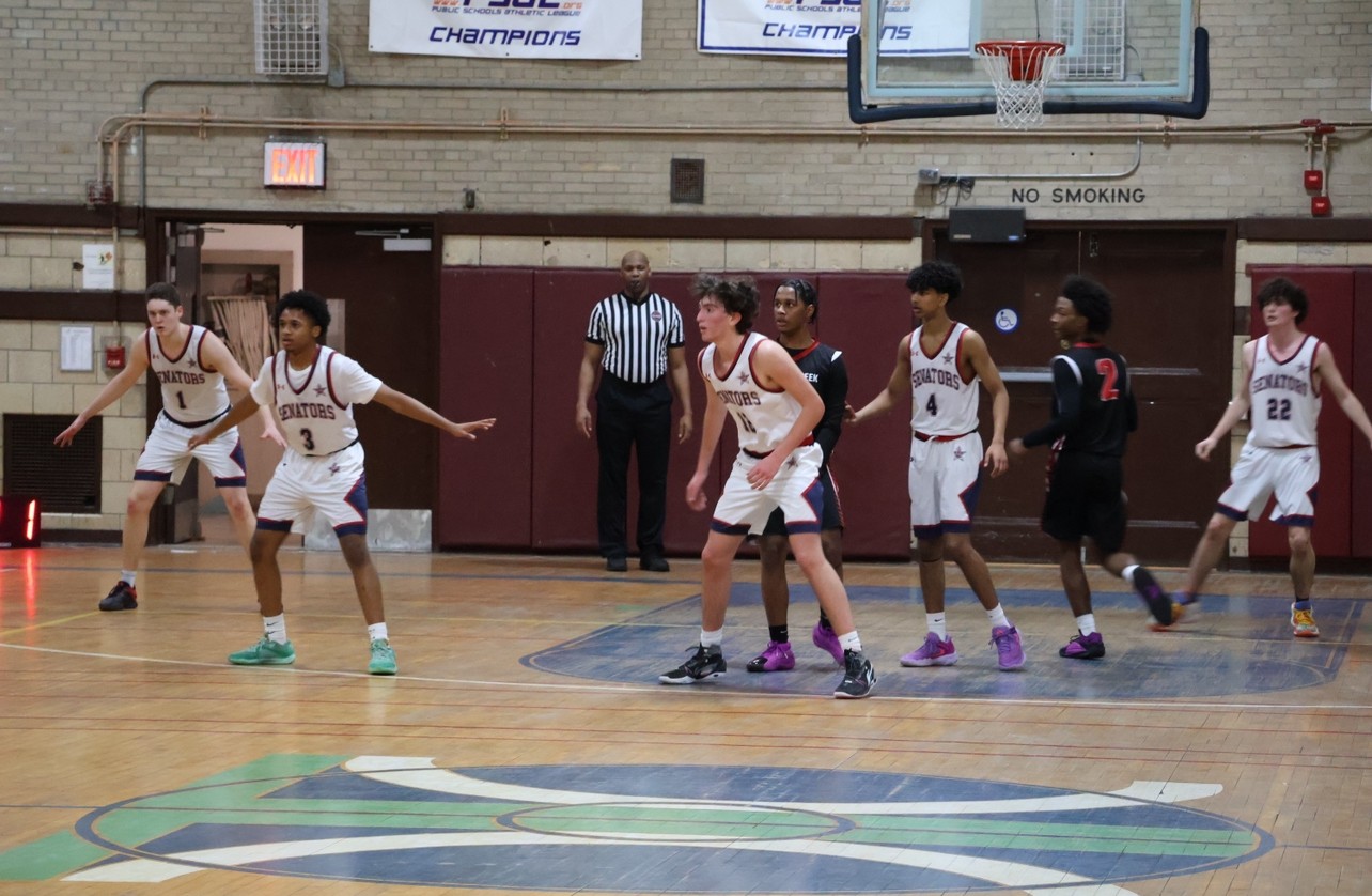 Boys defend the basket on a basketball court.