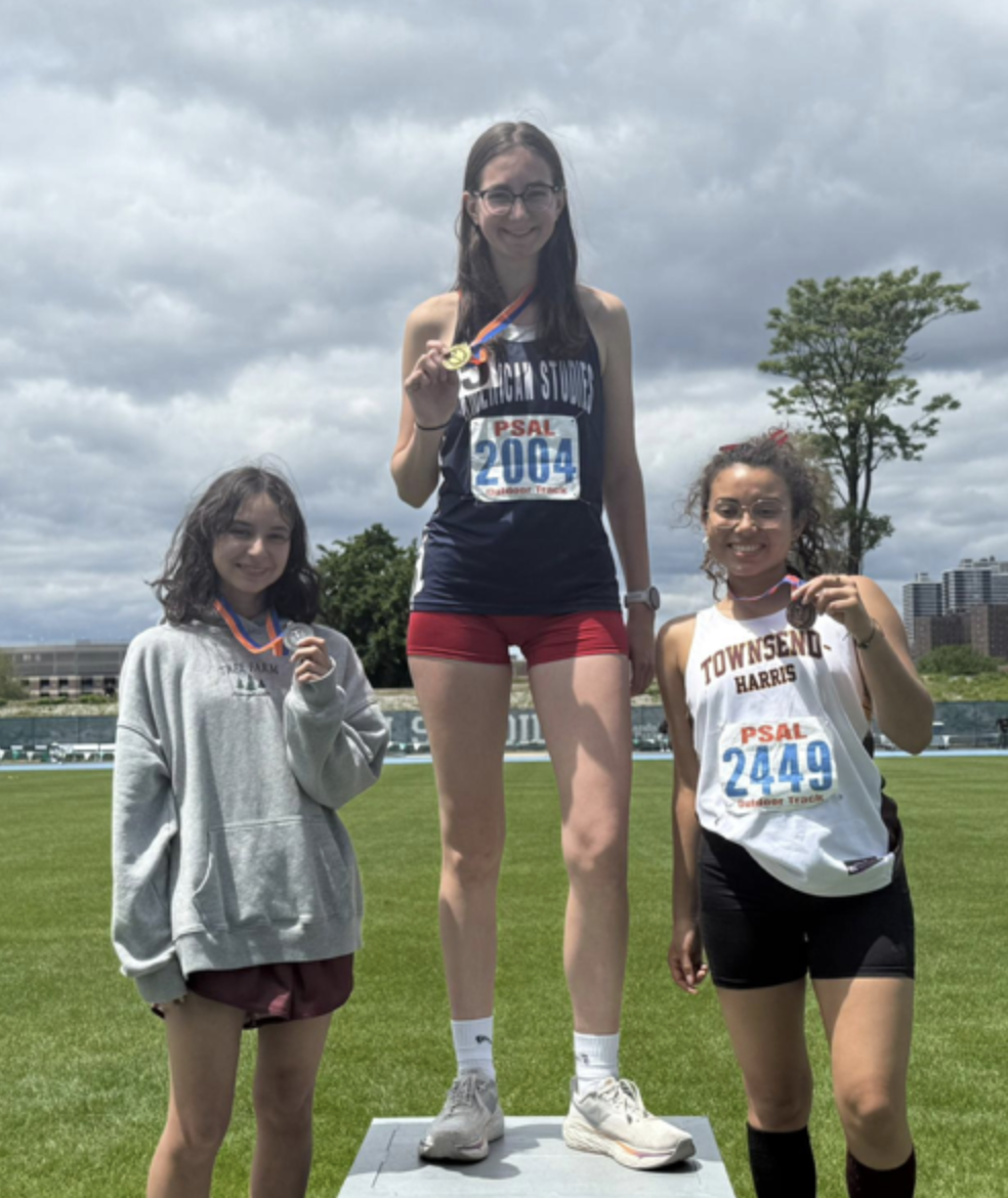 Student stands on a podium holding a medal.