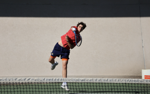 Player swings at tennis ball with a racquet.
