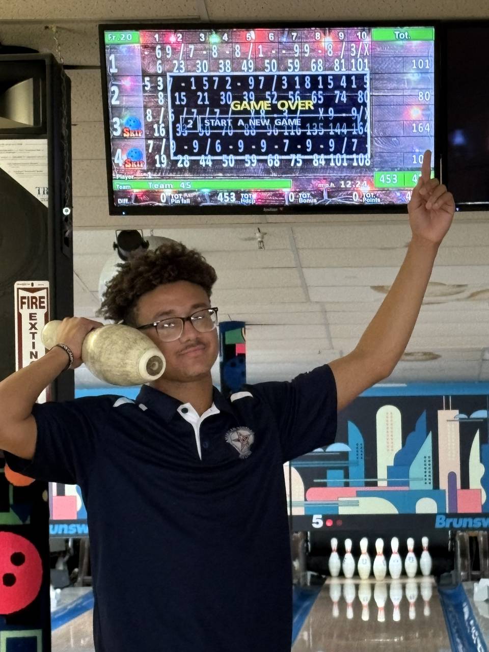 A student stands with a bowling pin his hand