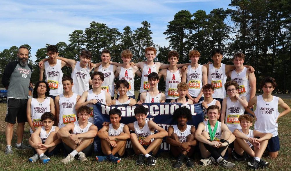 Members of the boys Cross Country Team pose with a banner.