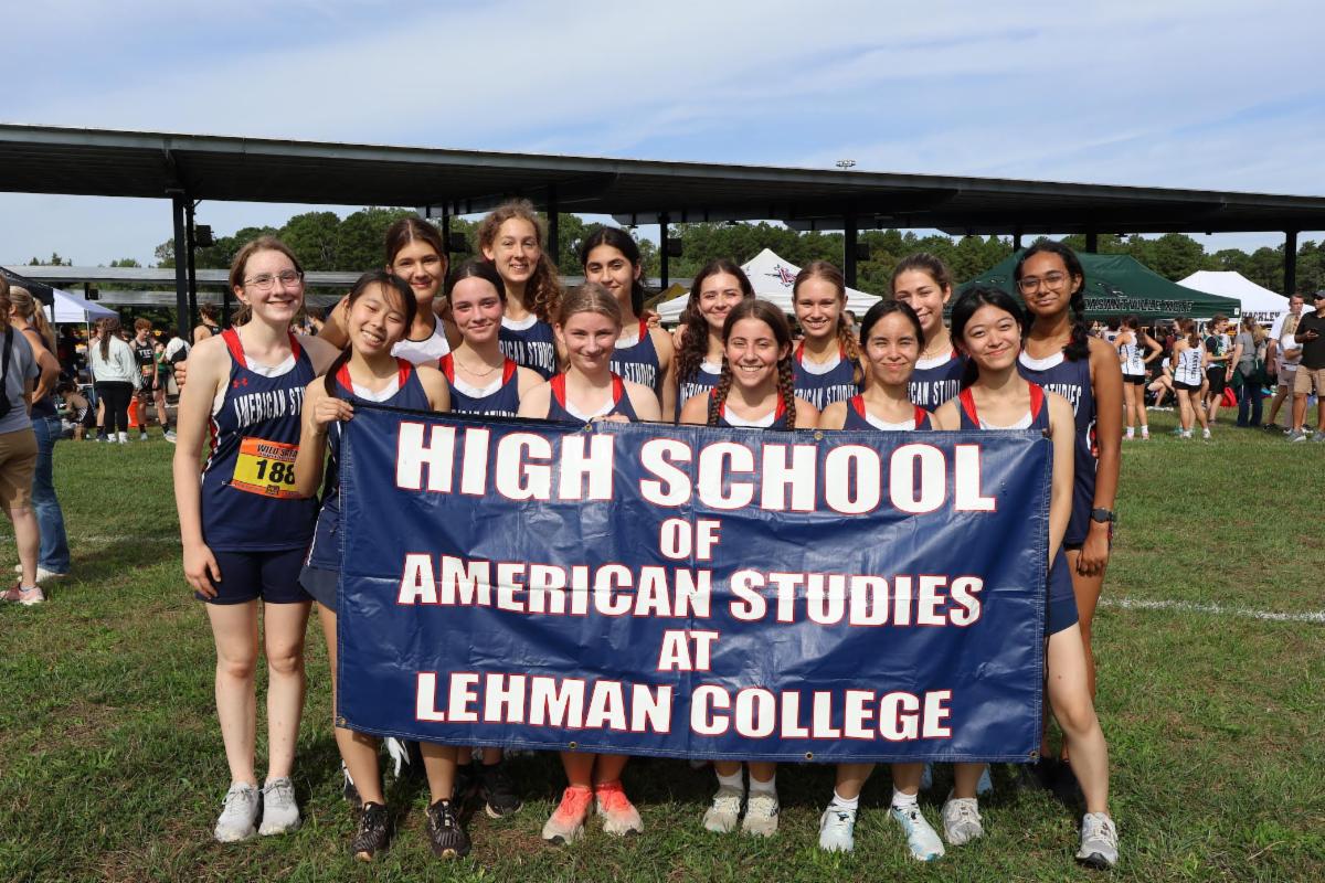 Members of the girl's Cross Country Team pose with a banner.