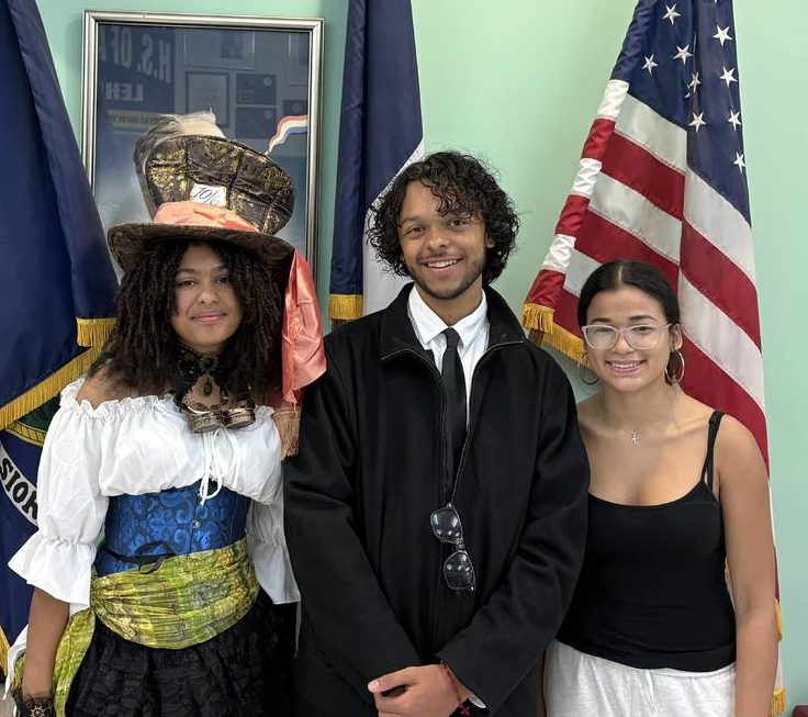 Three students stand shoulder to shoulder in front of flags