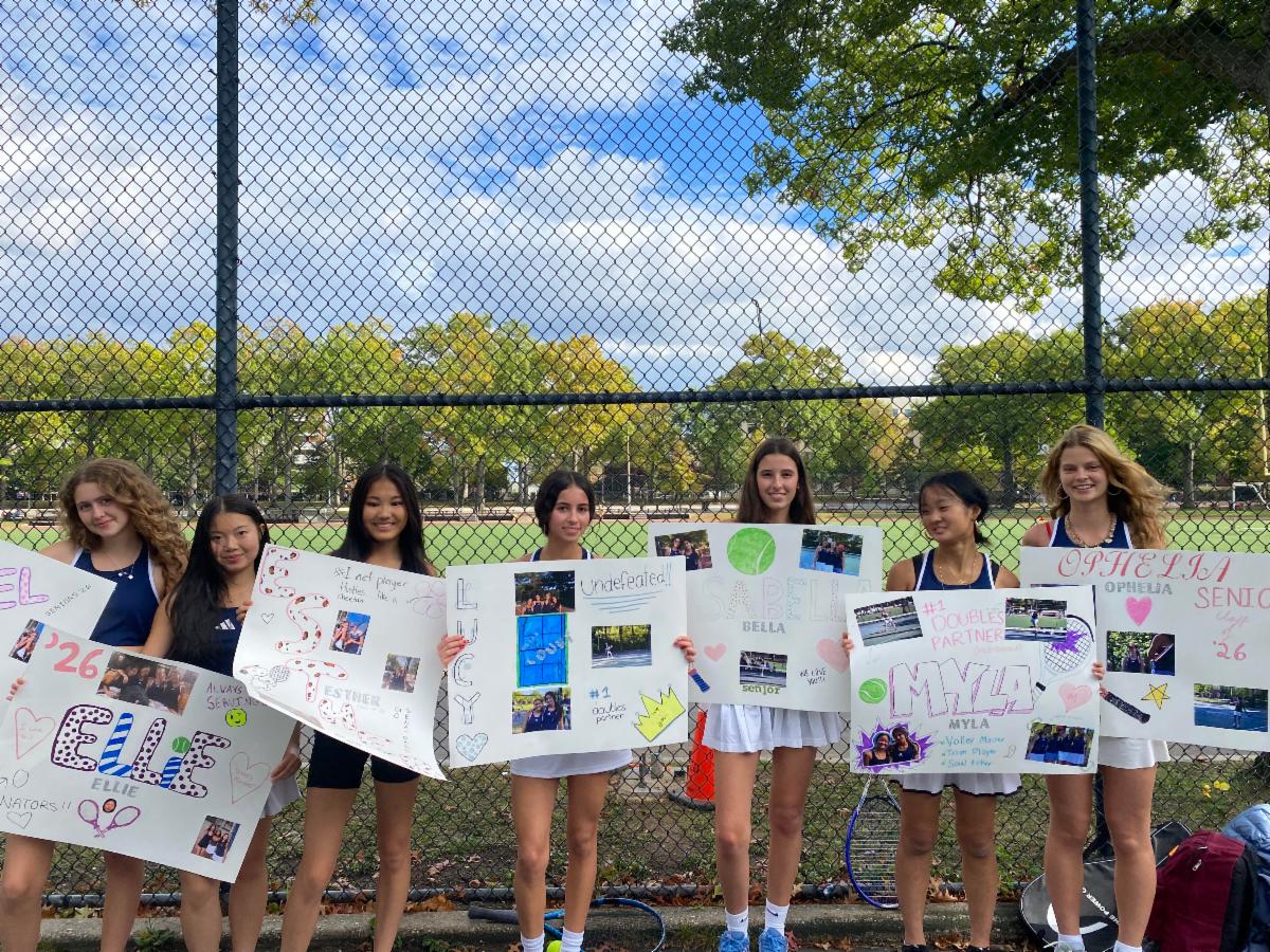 Six girls stand side by side holding signs