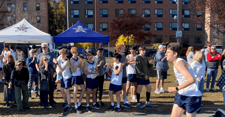 A Runner races past cheering teammates.