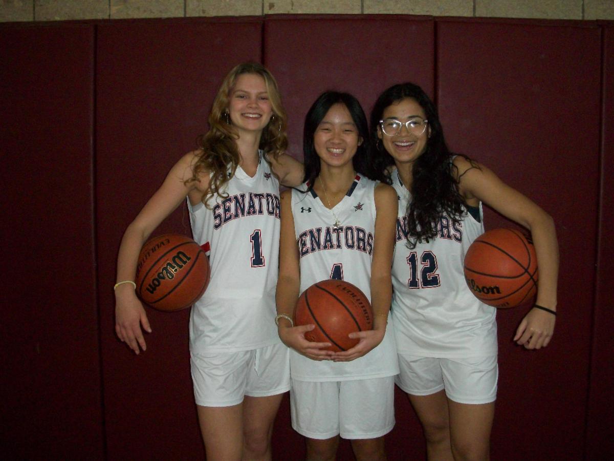 Three members of the girls basketball team stand side by side.