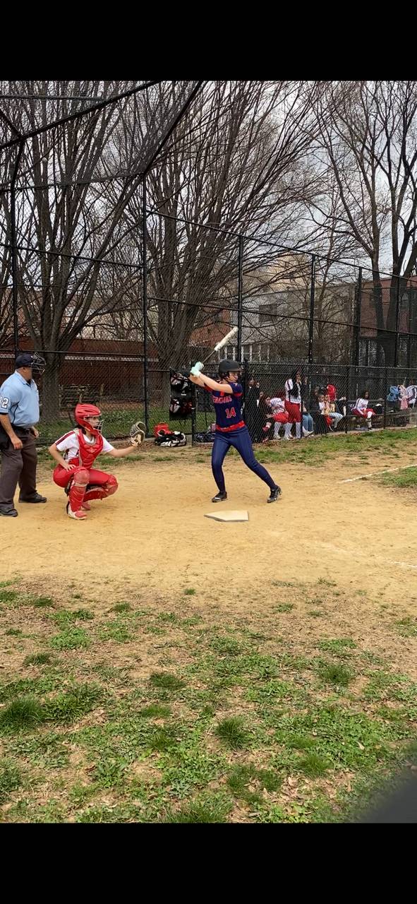 A Batter swing at a softball as a catcher positions behind them.