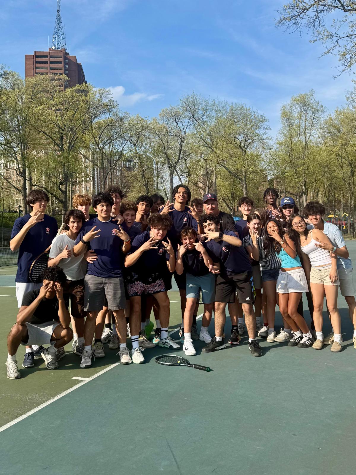 Memebers of a tennis team pose with hand gestures of V for victory.