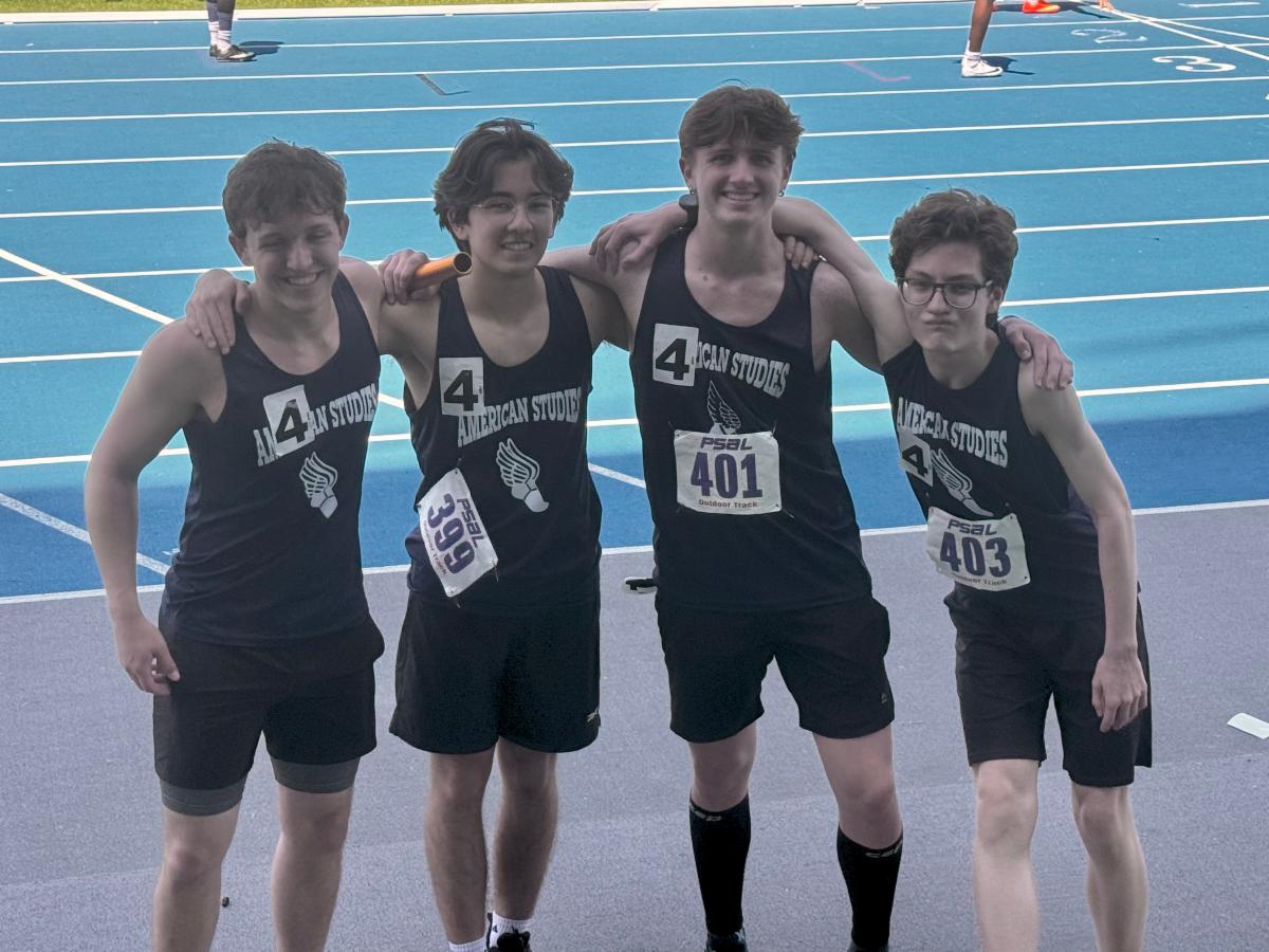 Boys on the relay team stand side by side holding a baton