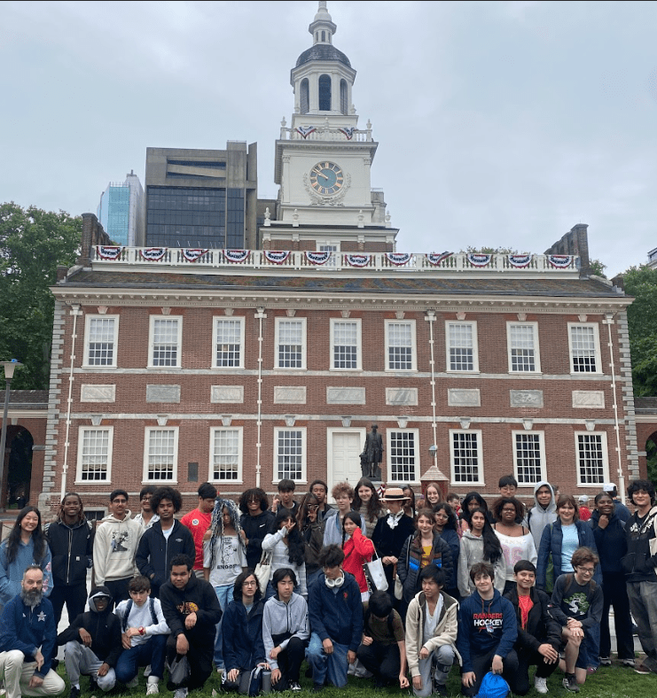 Dozens of students pose in three rows in front of Independence Hall.
