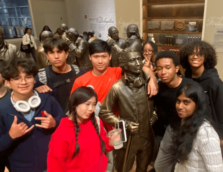 Students pose with a life size statue of Alexander Hamilton.