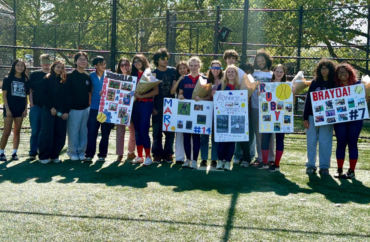 Members of the softball team hold of signs and posters celebrating seniors.