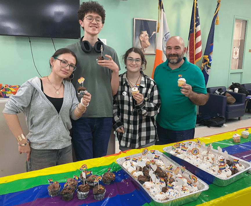 Three students and an adult hold cupcakes and pose for a picture.