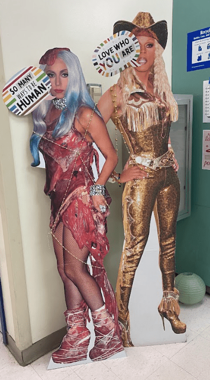 Two cardboard cut outs of celebrities stand in a hallway.