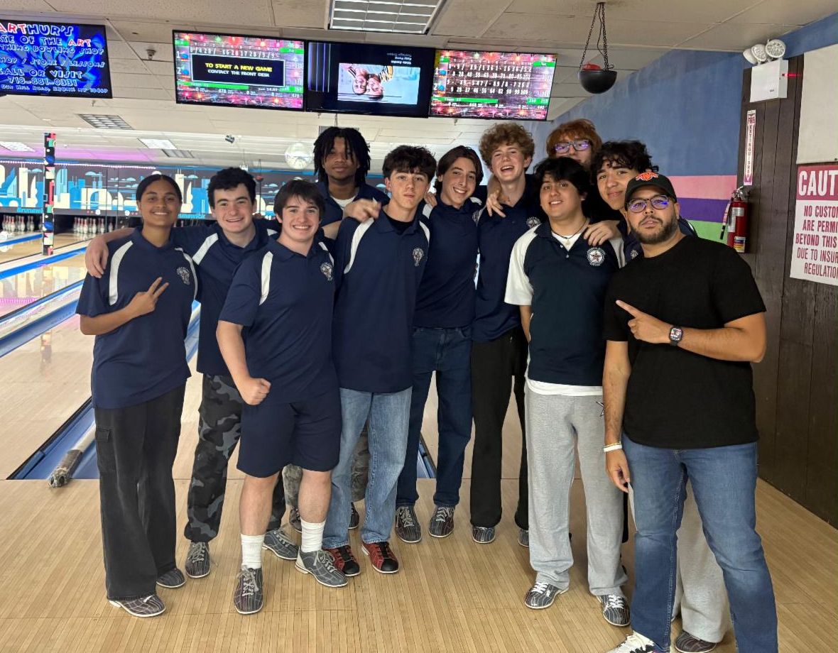 Members of the Bowling team pose with their coach in a bowling alley.