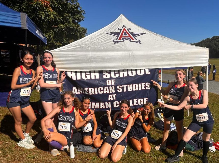 Members of the girls team stands in front a tent wearing uniforms.