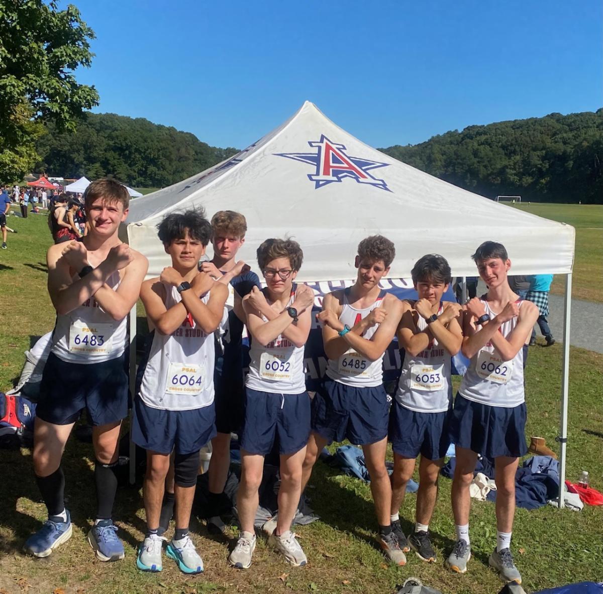 Members of the boys team stands in front a tent wearing uniforms.
